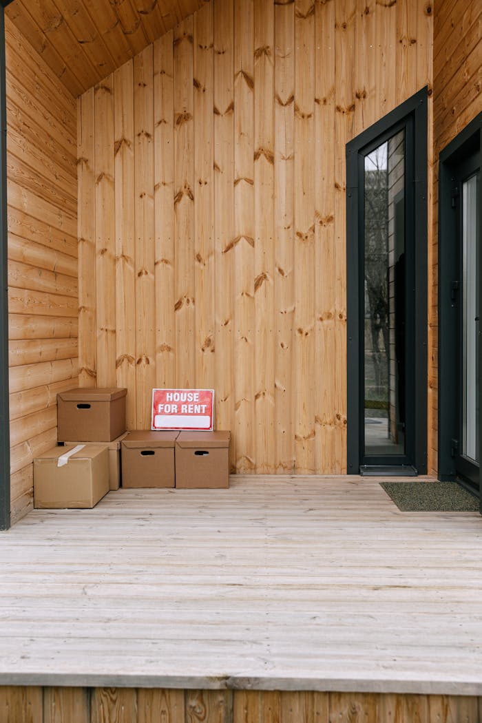 A wooden porch with boxes and 'House for Rent' sign, perfect for real estate listings.